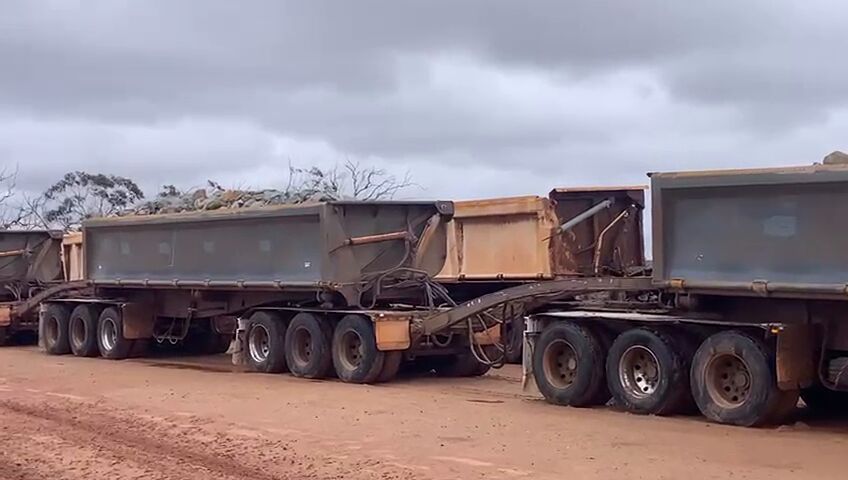 Loaded side-tipper road train on a red-dirt pad in the Goldfields