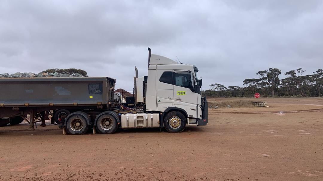 Volvo prime mover with side tipper on a red-dirt yard